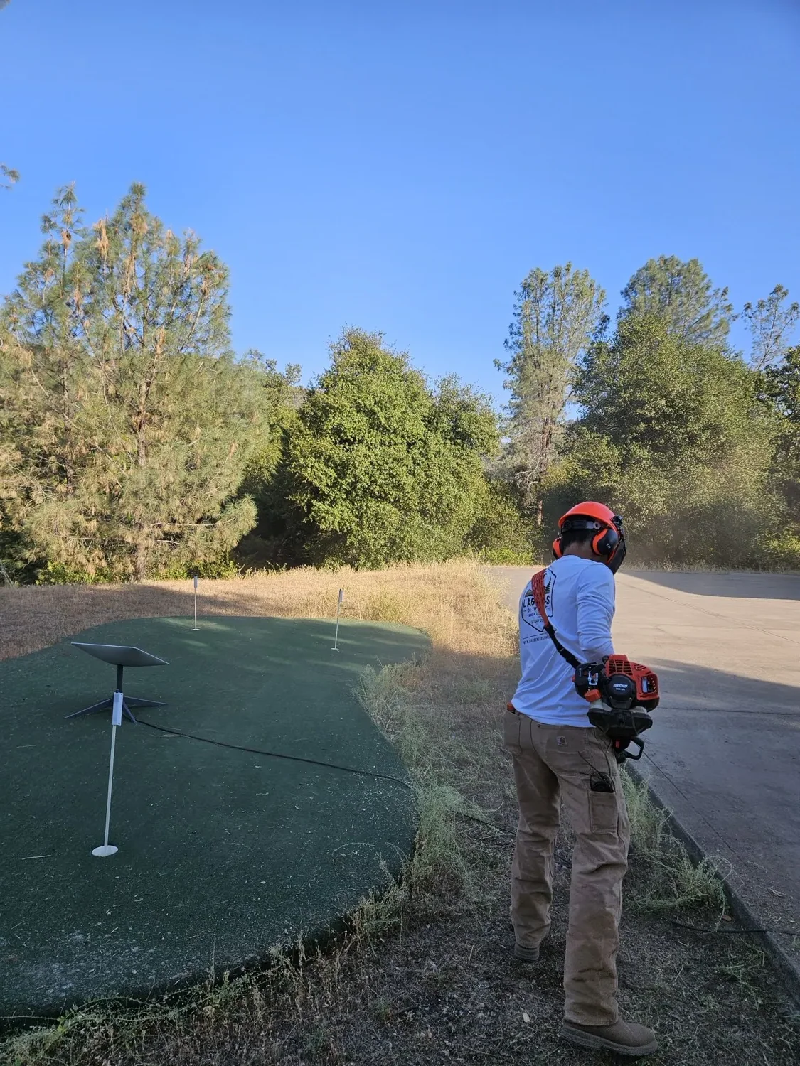 Crew member in helmet and ear protection cutting overgrowth with a brush cutter