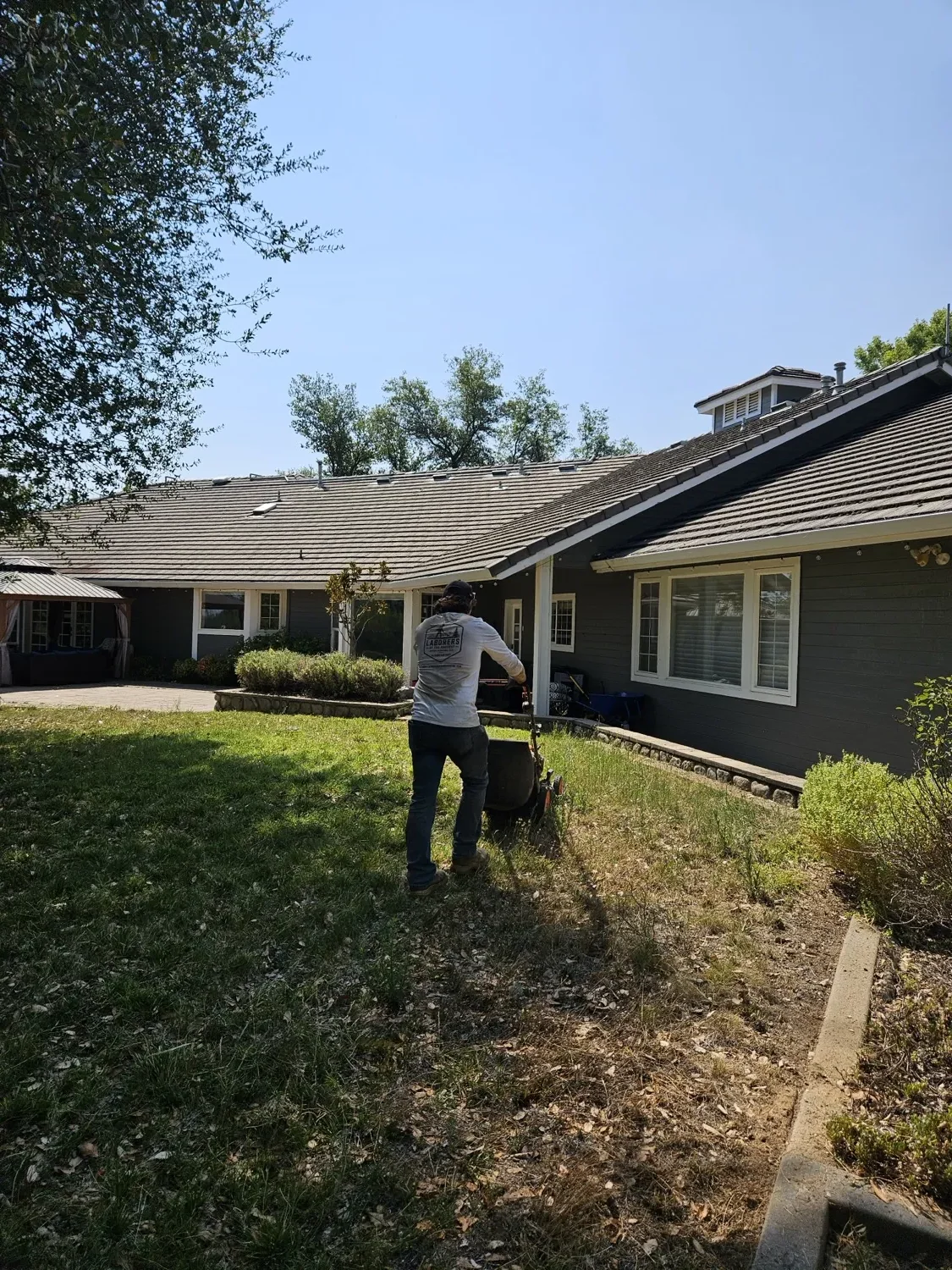 Crew member mowing the grounds behind a large home